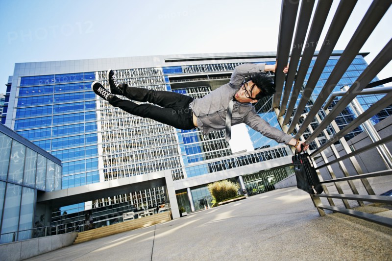 Asian businessman doing tricks on handrail