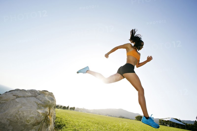 Hispanic woman running in rural landscape