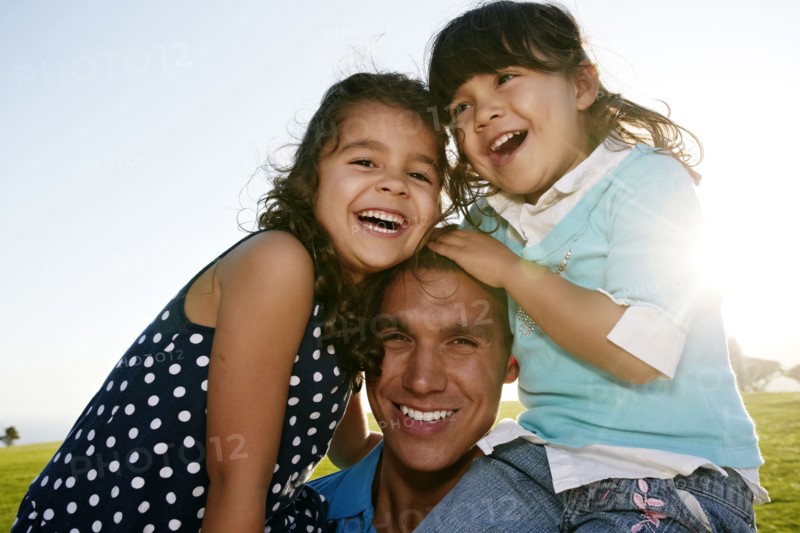 Father and daughters smiling in field