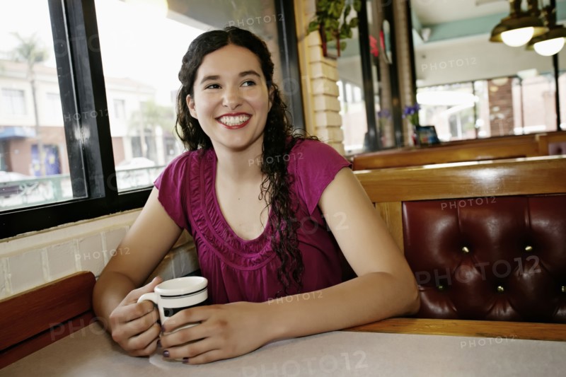 Mixed race woman having coffee in restaurant