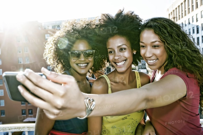 Mixed race women taking self-portrait on urban rooftop