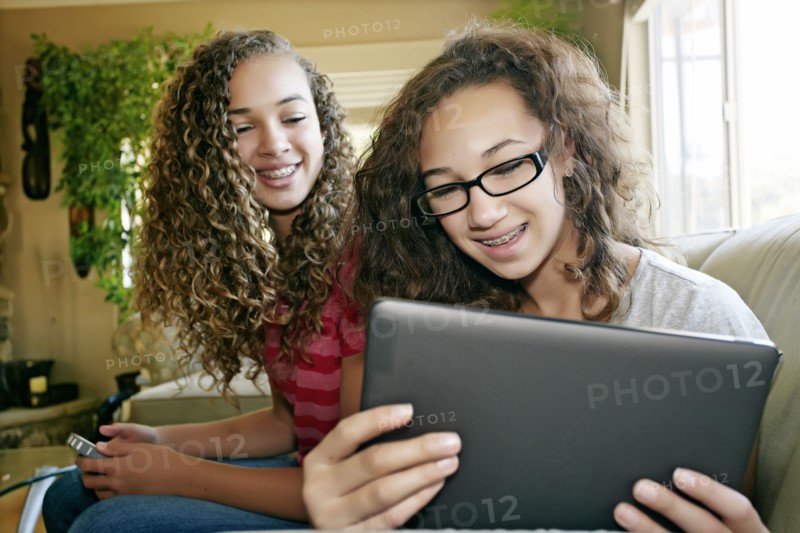 Mixed race teenage girls relaxing on sofa