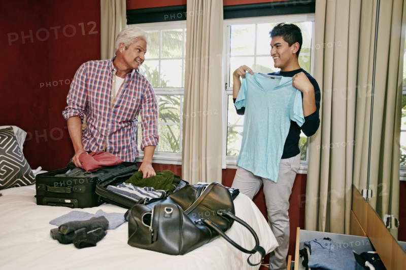 Homosexual couple packing suitcases in bedroom
