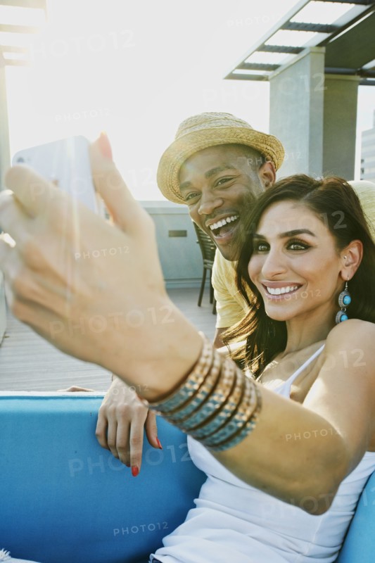 Couple taking self-portrait on sofa on balcony