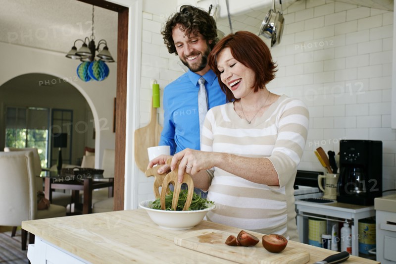 Pregnant Caucasian couple cooking in kitchen