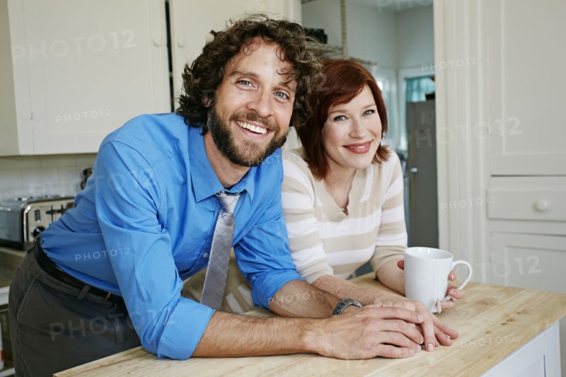 Pregnant Caucasian couple smiling in kitchen
