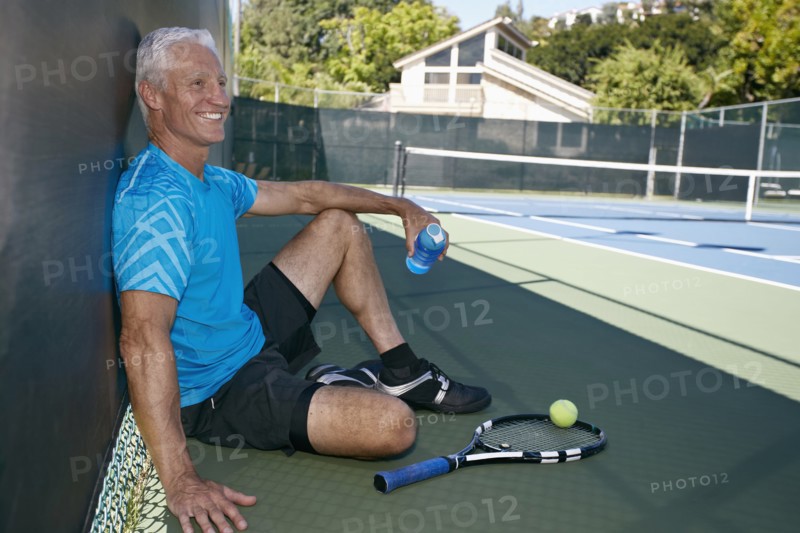 Caucasian man sitting on tennis court