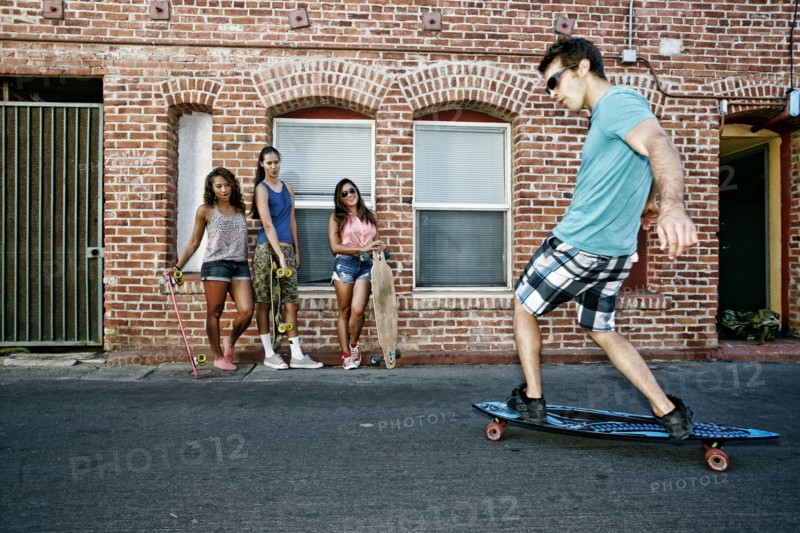 Friends riding longboards on city street
