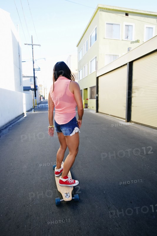 Woman riding longboard on city street