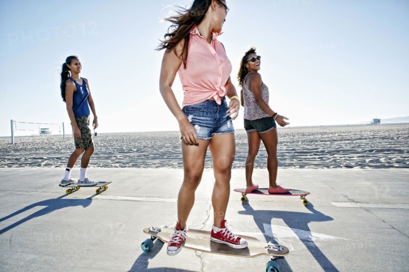 Friends riding longboards on beach