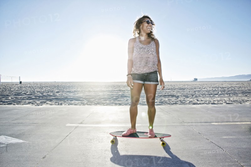 African American woman riding longboard on beach