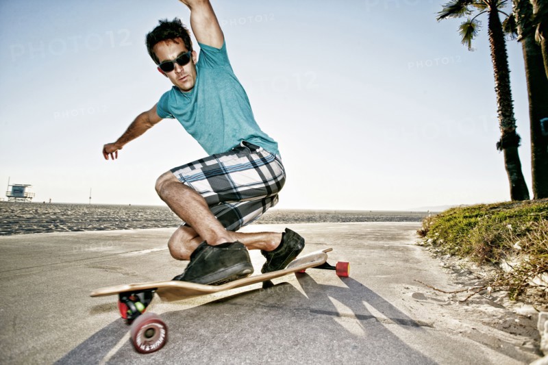 Caucasian man riding longboard on beach
