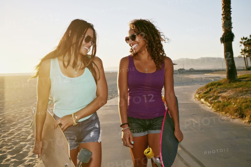 Women carrying longboards on beach