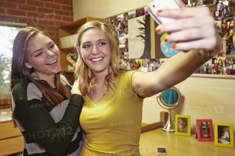 Caucasian students taking pictures in dorm room