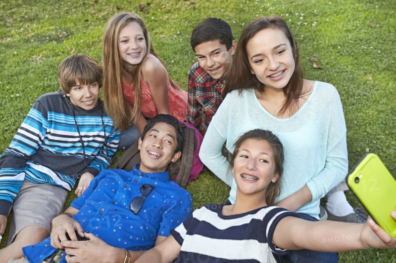 Teenagers taking picture together in grass