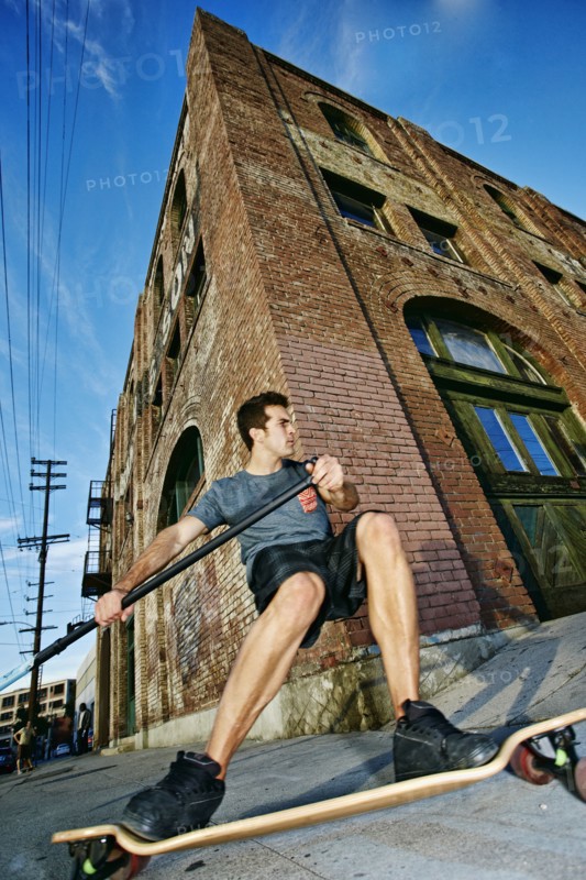 Caucasian man riding skateboard with land paddle