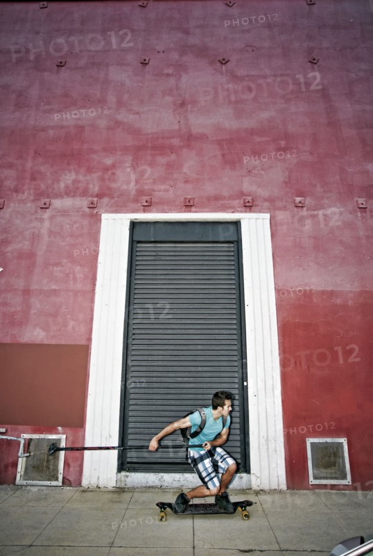 Caucasian man riding skateboard with land paddle