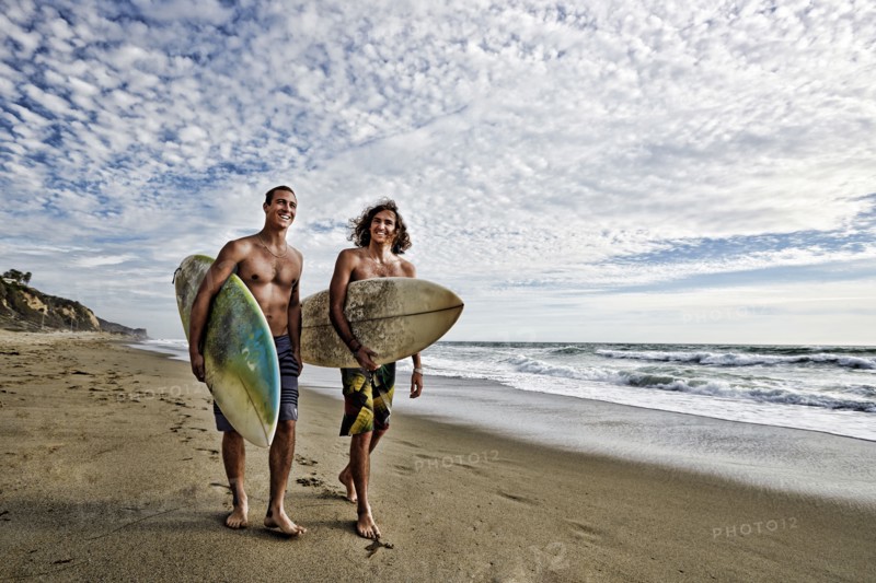 Caucasian men carrying surfboards on beach