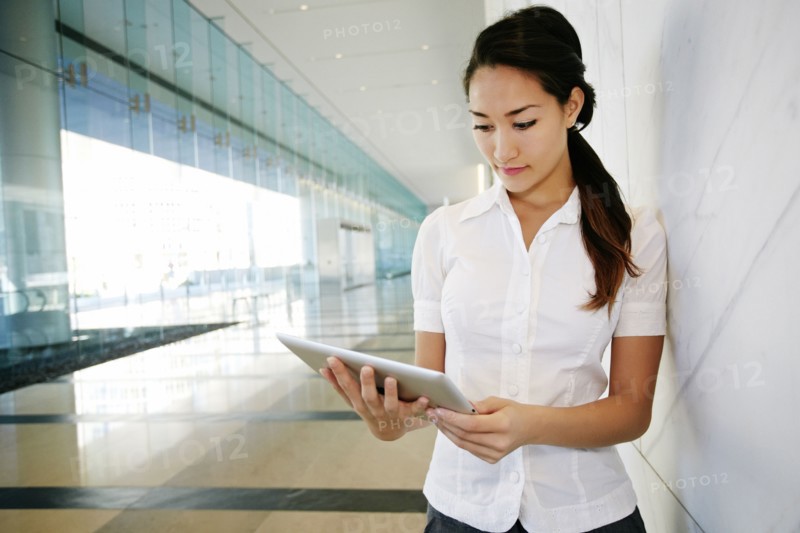 Mixed race businesswoman using tablet computer in lobby