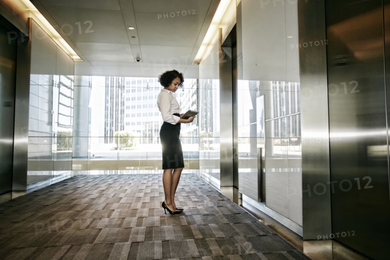 Mixed race businesswoman using tablet computer in lobby