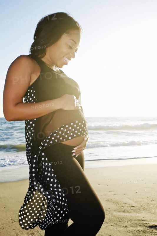Pregnant woman holding her belly on beach