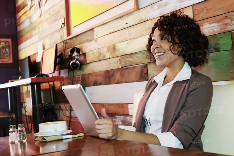 Mixed race woman using tablet computer in cafe