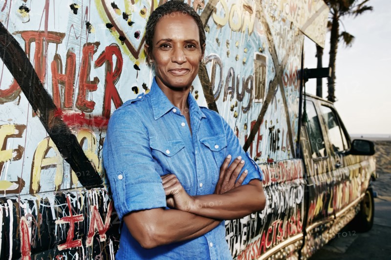 Older Black woman standing by decorated truck