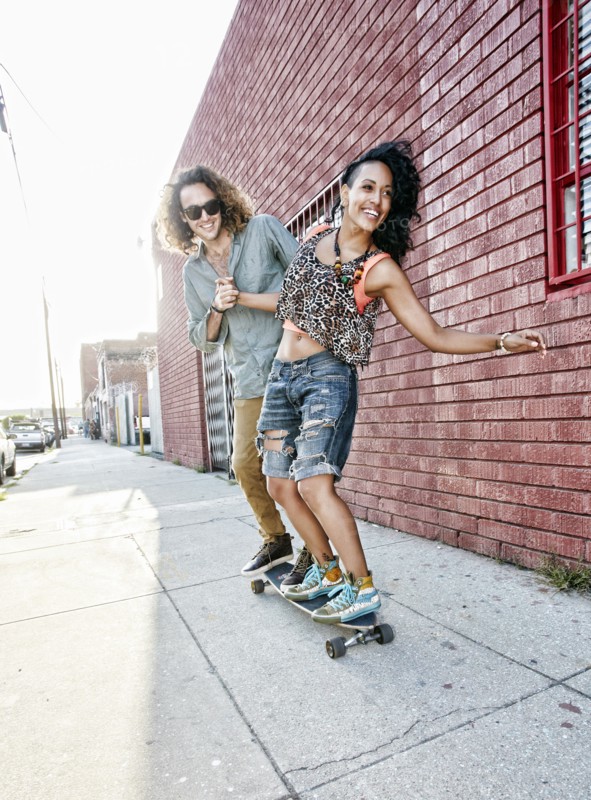 Couple riding skateboard on city street