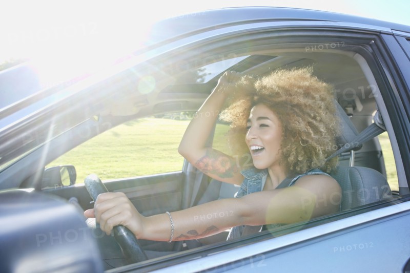 Hispanic woman cheering and driving car