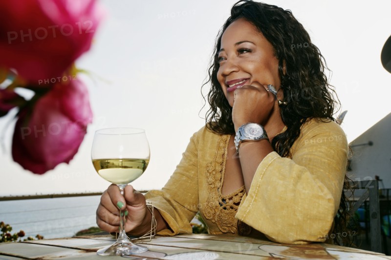 Mixed race woman drinking wine at waterfront