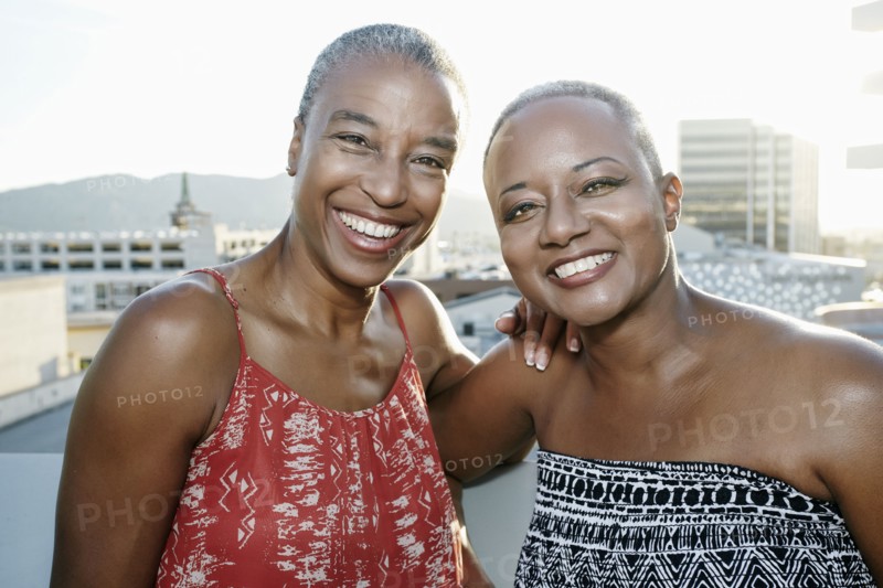 Black women smiling together on urban rooftop