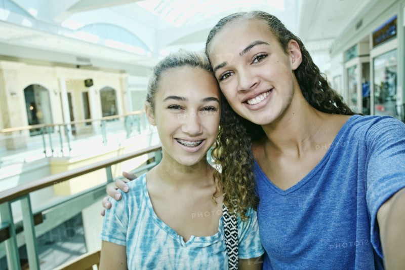Mixed race teenage girls smiling at shopping mall