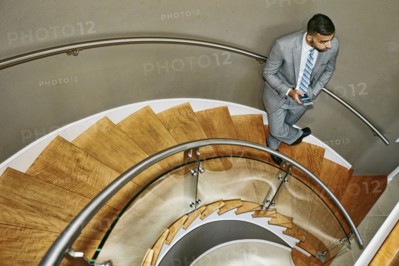 High angle view of Middle Eastern businessman standing on spiral staircase