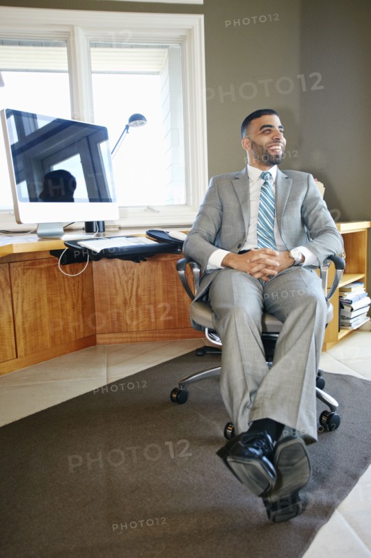 Middle Eastern businessman relaxing in chair at desk in office