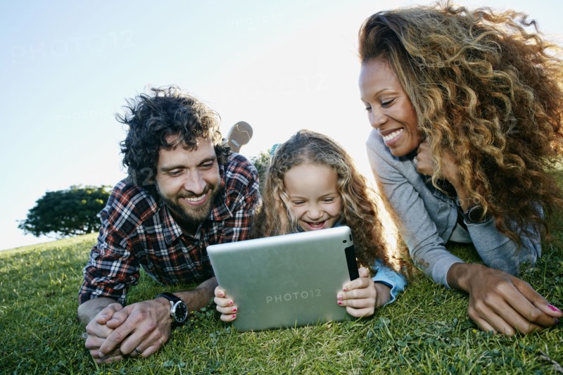 Family using digital tablet in grassy field