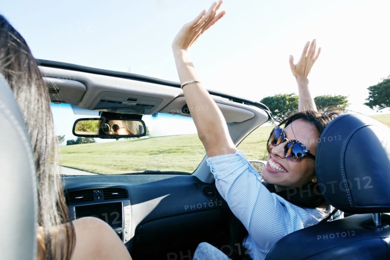 Excited women driving convertible on road trip