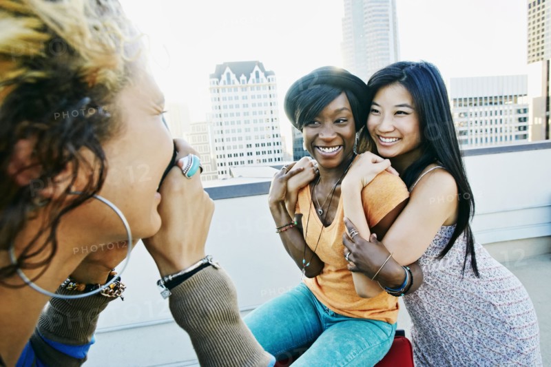 Woman photographing friends on urban rooftop