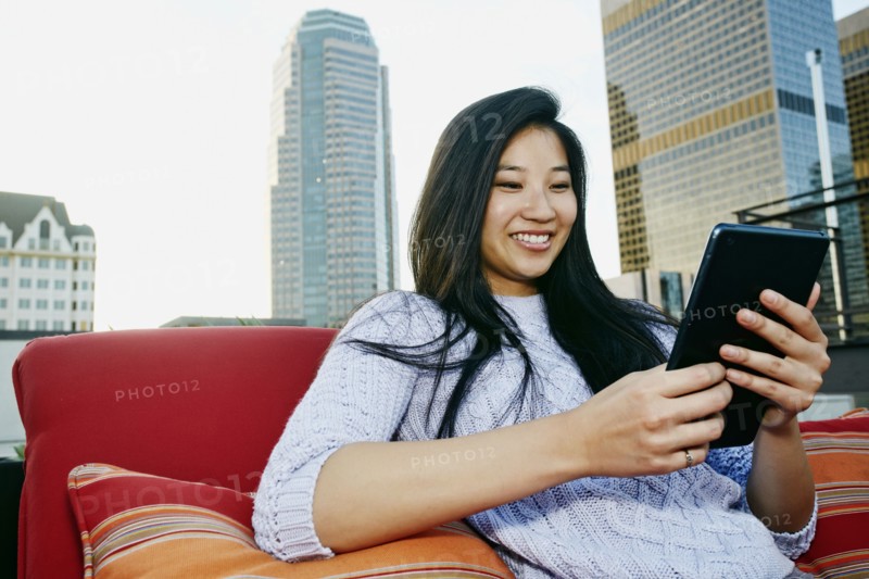 Chinese woman using digital tablet on urban rooftop