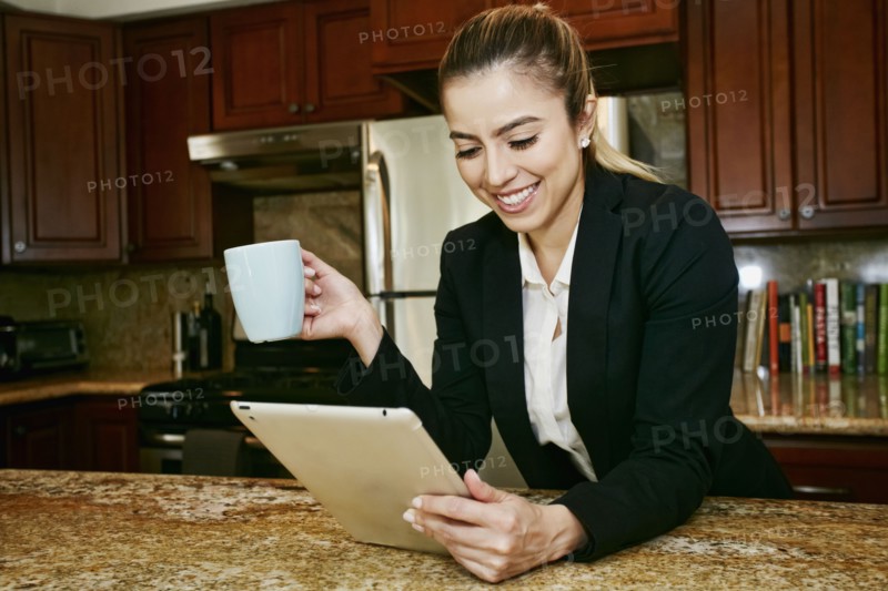 Caucasian businesswoman using digital tablet in kitchen