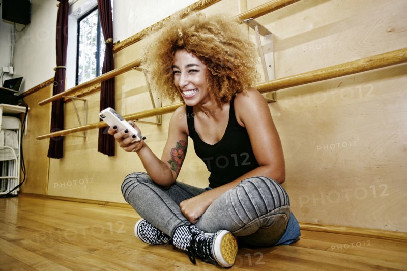 Hispanic dancer using cell phone in studio
