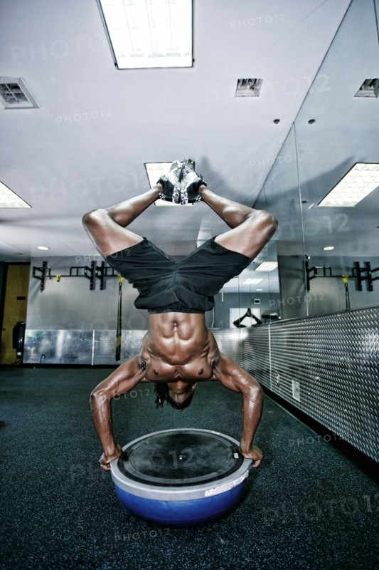 African American man doing handstand in gym