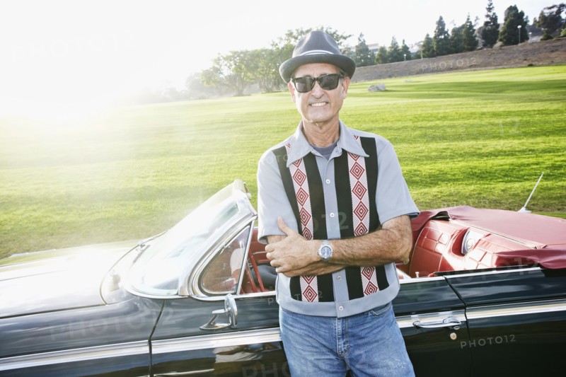 Mixed race man smiling near classic convertible