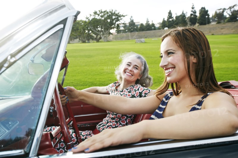 Mother and daughter driving in classic convertible