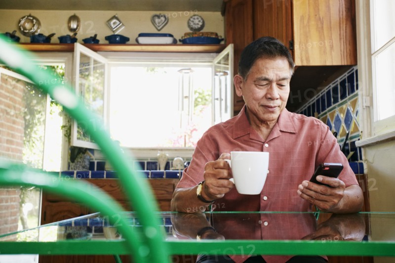 Filipino man using cell phone in kitchen