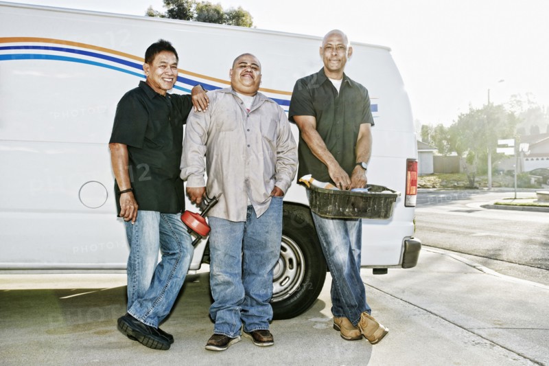 Plumbers smiling near van