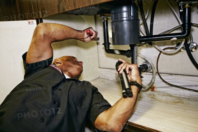 Mixed race plumber working under sink