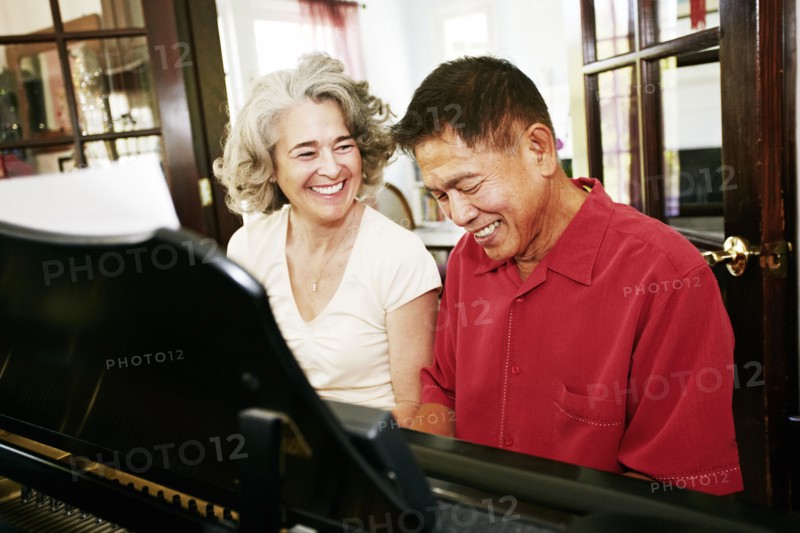 Couple playing piano together in living room