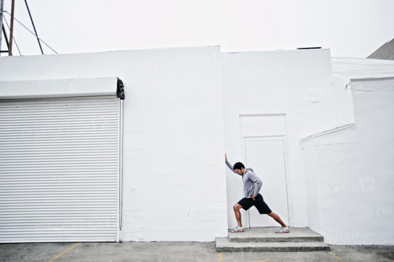 Mixed race man stretching in doorway