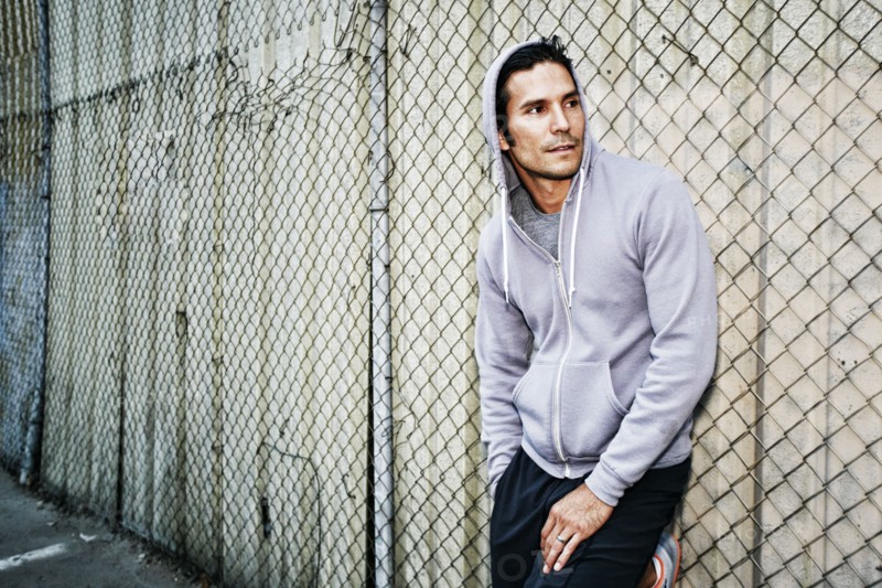 Mixed race man leaning on chain link fence