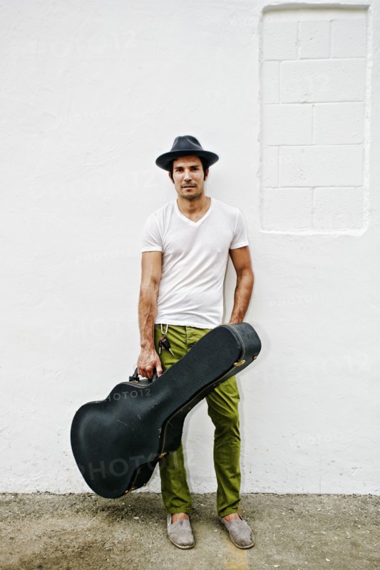 Mixed race musician carrying guitar case